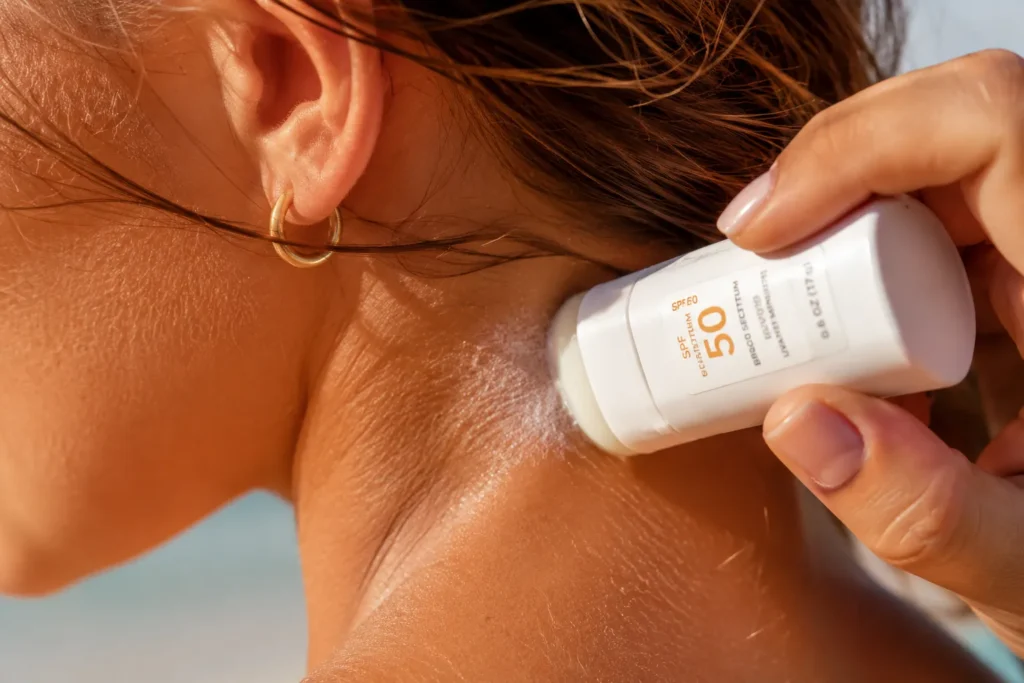 11 Vacation Sunscreen Tips for Beach Days That Actually Work 4 Close up of stick sunscreen being applied to the back of the neck and ears