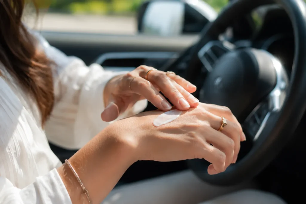 10 Skin Protection Secrets for a Youthful Glow 10 Woman applying sunscreen to her hand while sitting in a car